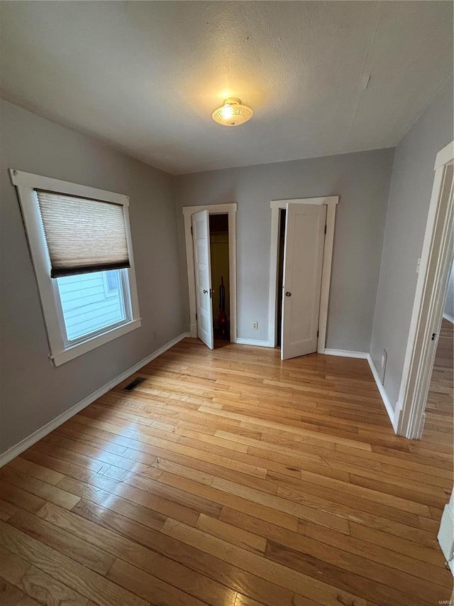 unfurnished bedroom featuring light wood-type flooring, visible vents, and baseboards