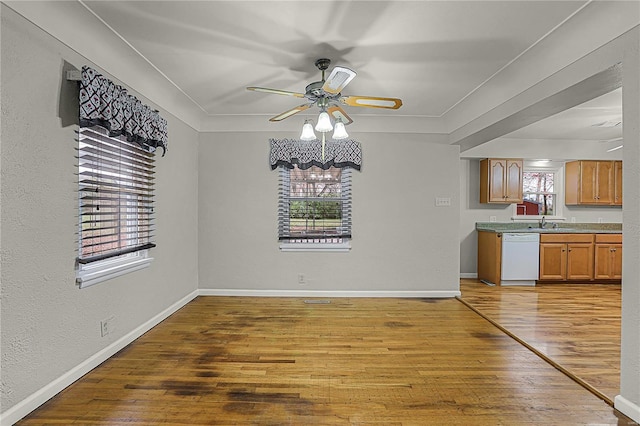 unfurnished dining area with plenty of natural light, baseboards, ceiling fan, and light wood finished floors