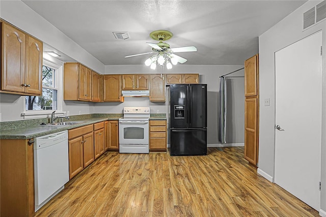 kitchen with white appliances, visible vents, dark countertops, under cabinet range hood, and a sink