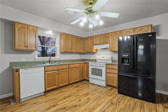 kitchen featuring under cabinet range hood, white appliances, a sink, light wood-style floors, and dark countertops