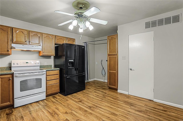 kitchen featuring visible vents, white electric range, light wood-type flooring, under cabinet range hood, and black fridge