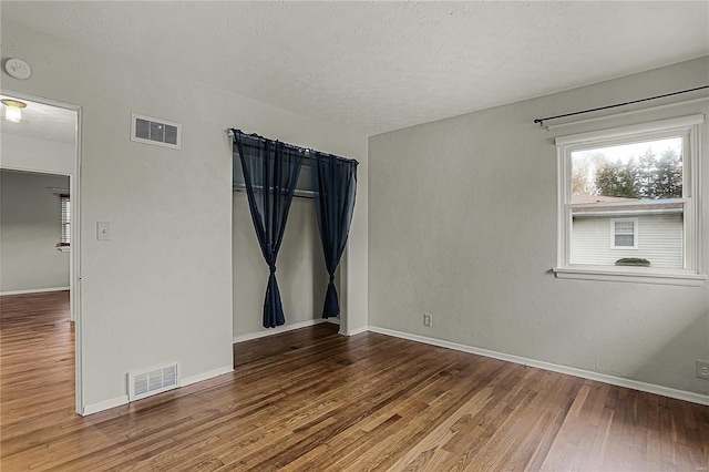 unfurnished room featuring wood finished floors, visible vents, and baseboards