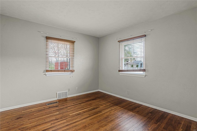 unfurnished room featuring visible vents, baseboards, and wood finished floors