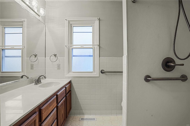 full bathroom featuring visible vents, tile walls, a wealth of natural light, and vanity