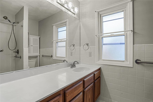 full bath featuring toilet, vanity, and tile walls