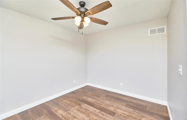 empty room with a ceiling fan, baseboards, visible vents, and wood finished floors