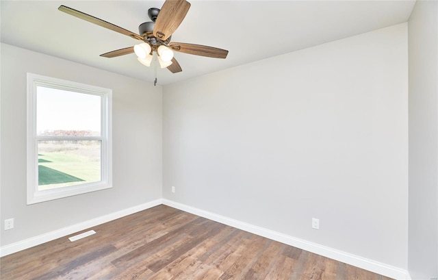 empty room featuring a ceiling fan, visible vents, baseboards, and dark wood-type flooring