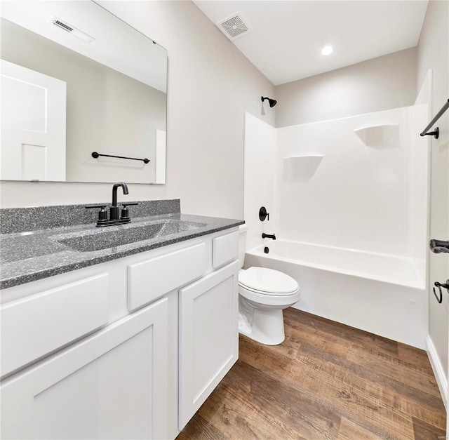 bathroom with washtub / shower combination, toilet, wood finished floors, and visible vents