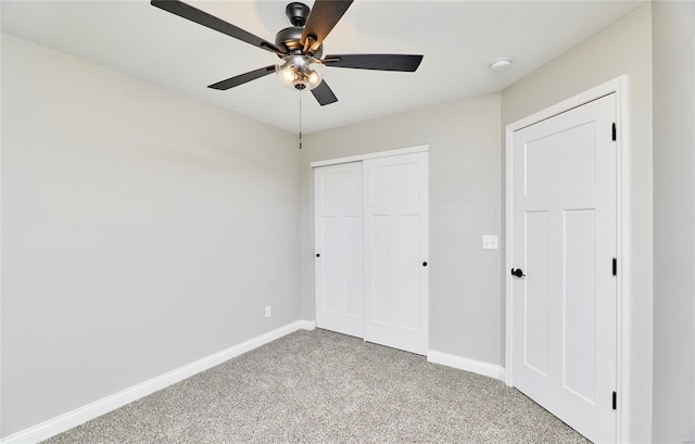 unfurnished bedroom with light carpet, a closet, a ceiling fan, and baseboards