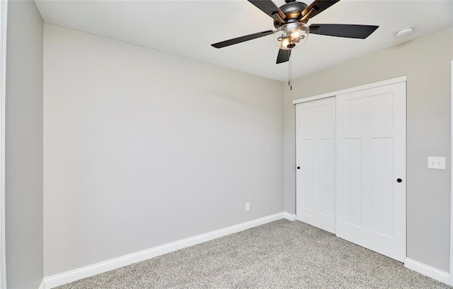 unfurnished bedroom featuring a closet, light colored carpet, ceiling fan, and baseboards