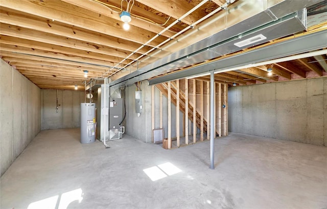 unfinished below grade area featuring electric panel, water heater, visible vents, and heating unit