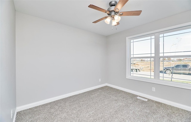 carpeted empty room featuring baseboards, visible vents, and ceiling fan