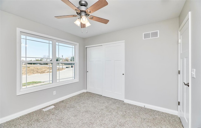 unfurnished bedroom with a closet, visible vents, light carpet, and baseboards