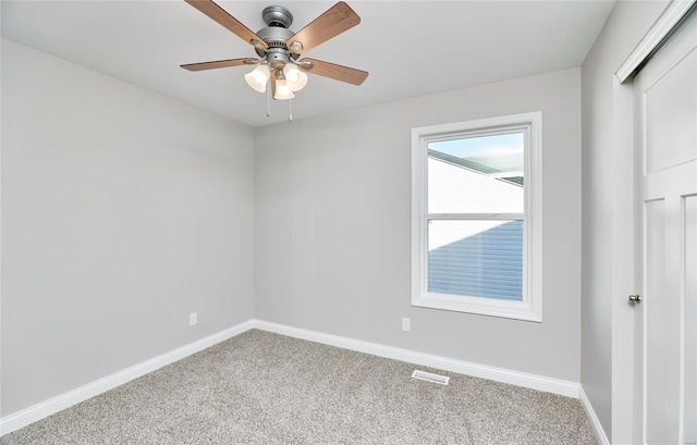 carpeted empty room featuring a ceiling fan, visible vents, and baseboards