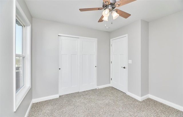 unfurnished bedroom with ceiling fan, a closet, baseboards, and carpet flooring