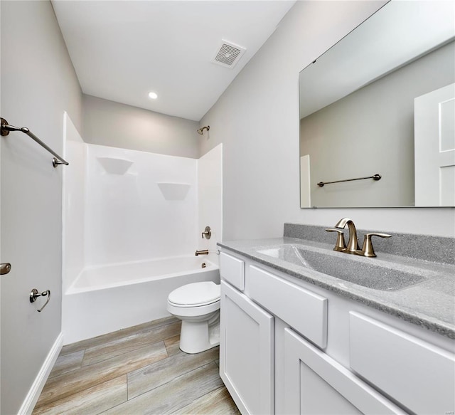 full bathroom with visible vents, toilet, wood finished floors, vanity, and shower / washtub combination