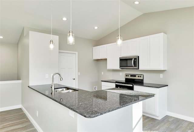 kitchen featuring a sink, white cabinetry, hanging light fixtures, appliances with stainless steel finishes, and dark stone countertops