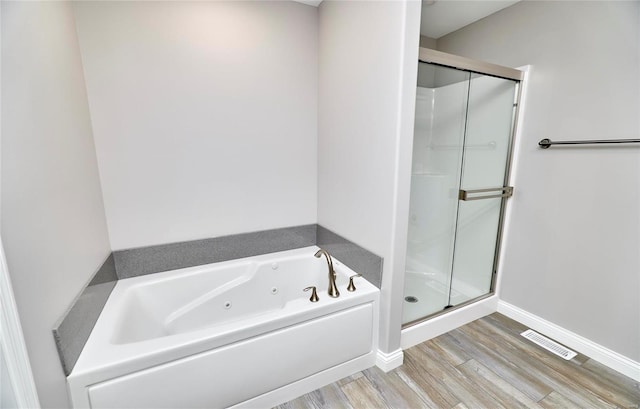 bathroom featuring wood finished floors, visible vents, baseboards, a whirlpool tub, and a stall shower