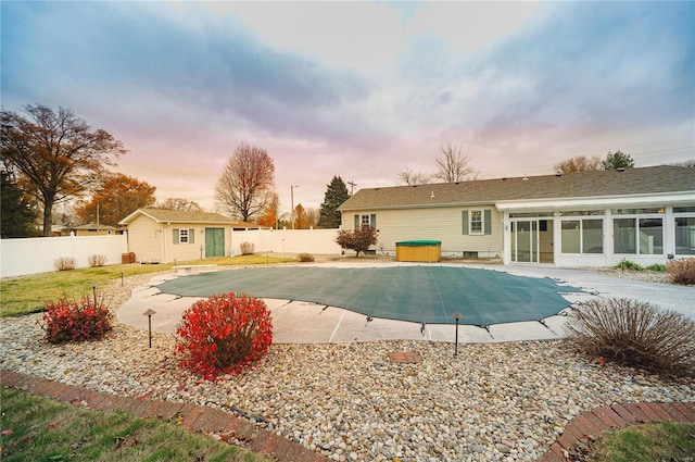 pool at dusk featuring a fenced in pool, an outbuilding, a patio area, and a fenced backyard