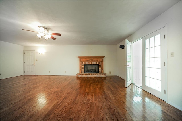 unfurnished living room featuring dark wood-style flooring, a fireplace, baseboards, and ceiling fan