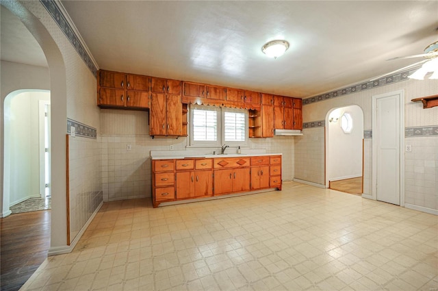 kitchen featuring arched walkways, light floors, a sink, light countertops, and open shelves