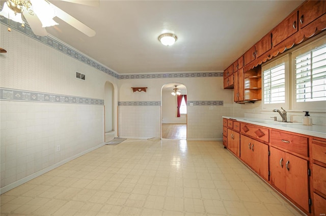 kitchen featuring wallpapered walls, arched walkways, light countertops, light floors, and open shelves