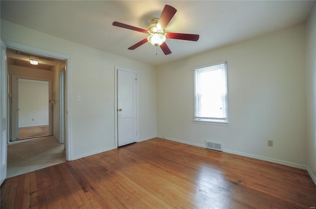 unfurnished bedroom featuring a ceiling fan, visible vents, light wood-style flooring, and baseboards