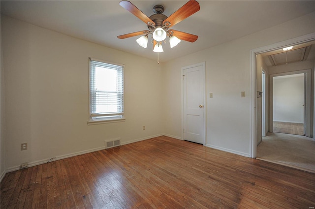 unfurnished bedroom featuring attic access, baseboards, visible vents, ceiling fan, and wood finished floors