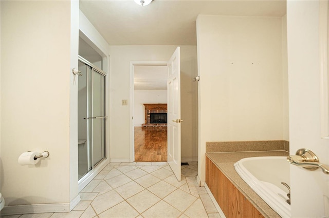 bathroom featuring a washtub, tile patterned flooring, a fireplace, and a shower stall