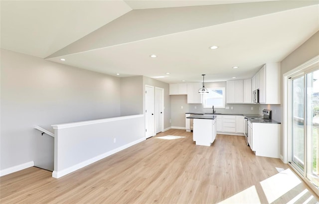 kitchen with stainless steel appliances, a sink, white cabinetry, light wood finished floors, and dark countertops