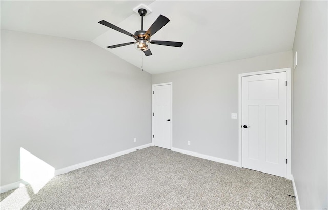 carpeted empty room featuring vaulted ceiling, a ceiling fan, and baseboards