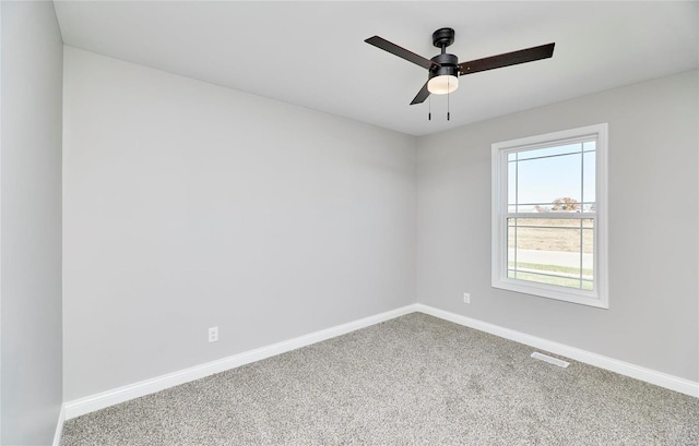 carpeted spare room with visible vents, baseboards, and a ceiling fan