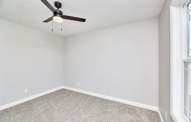 carpeted spare room featuring baseboards and a ceiling fan