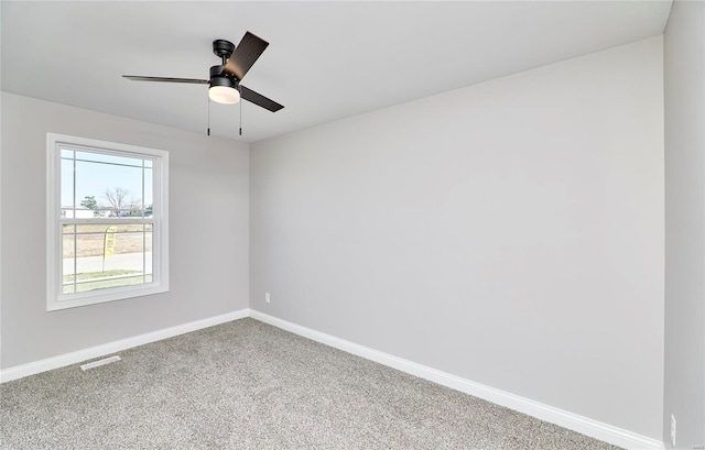 carpeted spare room featuring visible vents, ceiling fan, and baseboards