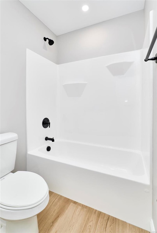 bathroom with bathtub / shower combination, wood finished floors, and toilet