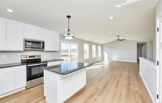 kitchen featuring decorative light fixtures, dark countertops, appliances with stainless steel finishes, open floor plan, and a kitchen island