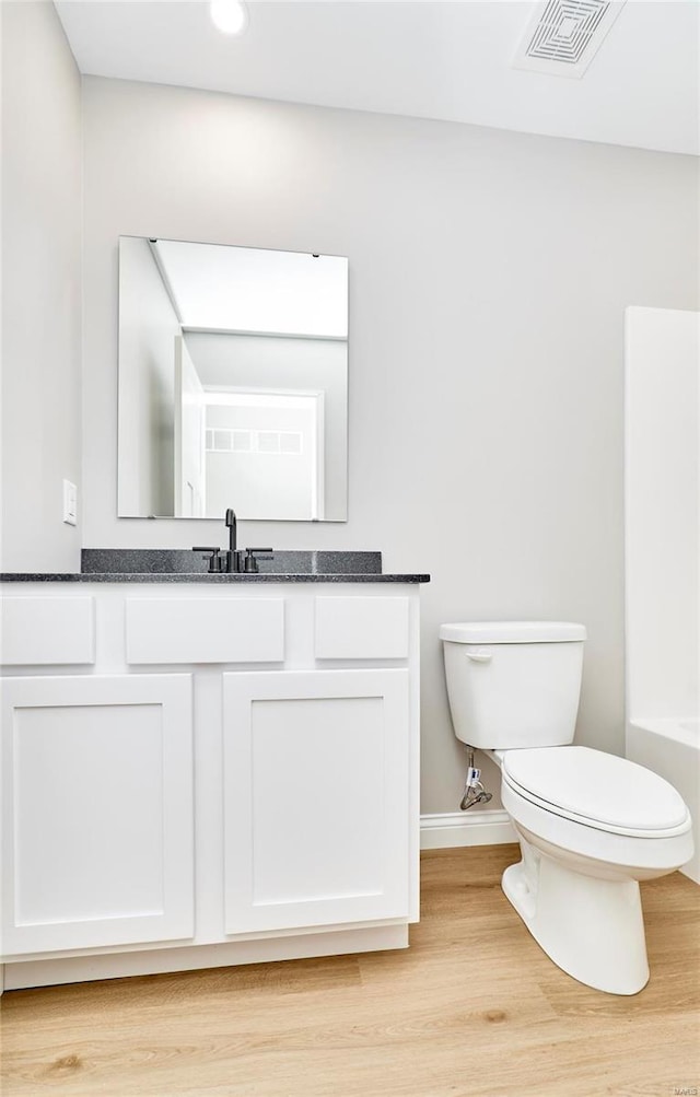 bathroom with toilet, wood finished floors, vanity, visible vents, and baseboards