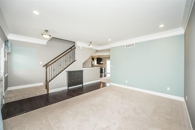 unfurnished living room featuring baseboards, stairs, visible vents, and crown molding