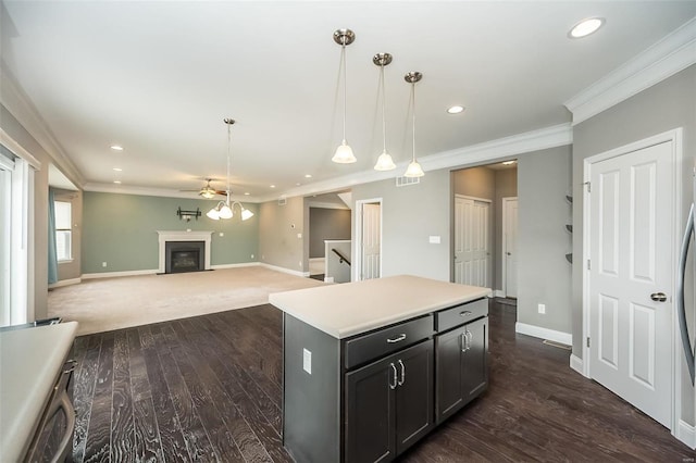 kitchen with baseboards, hanging light fixtures, a center island, a glass covered fireplace, and crown molding