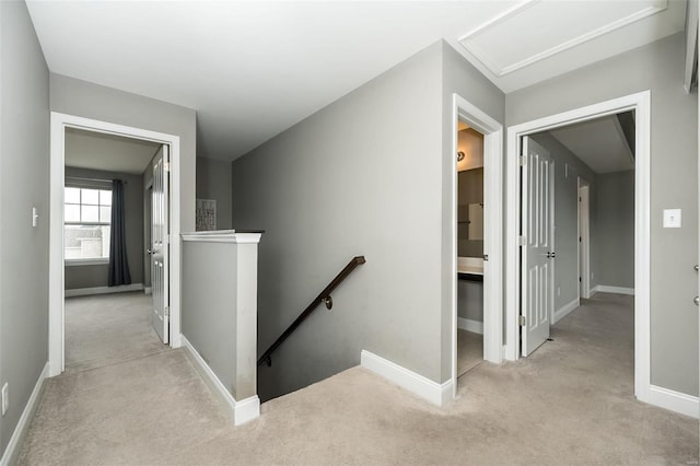 hall with carpet floors, baseboards, and an upstairs landing