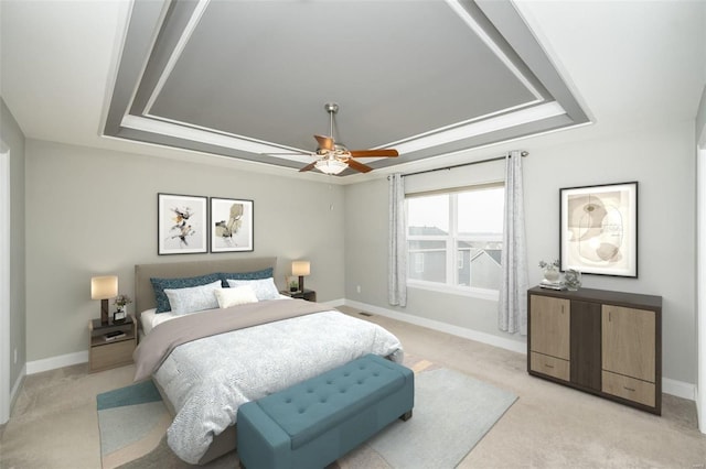 bedroom with light carpet, a tray ceiling, and baseboards