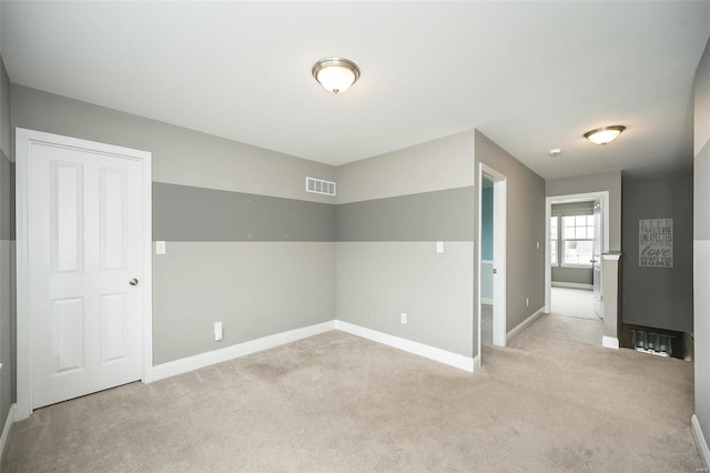 spare room featuring light carpet, visible vents, and baseboards