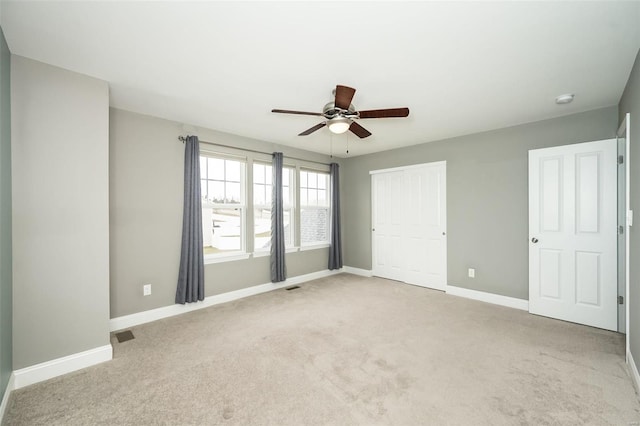 unfurnished bedroom featuring baseboards, a closet, visible vents, and light colored carpet