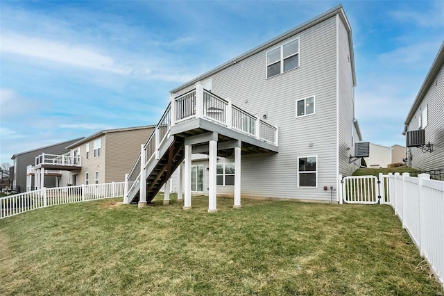 rear view of house with a fenced backyard, stairway, a wooden deck, and a yard