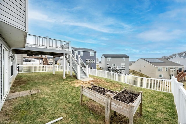 view of yard with a garden, a fenced backyard, a residential view, stairway, and a deck