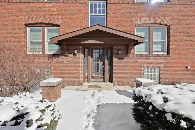 snow covered property entrance with brick siding