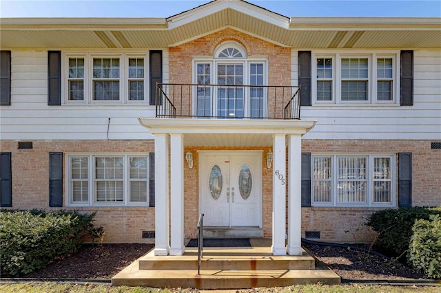 doorway to property with a balcony, crawl space, and brick siding