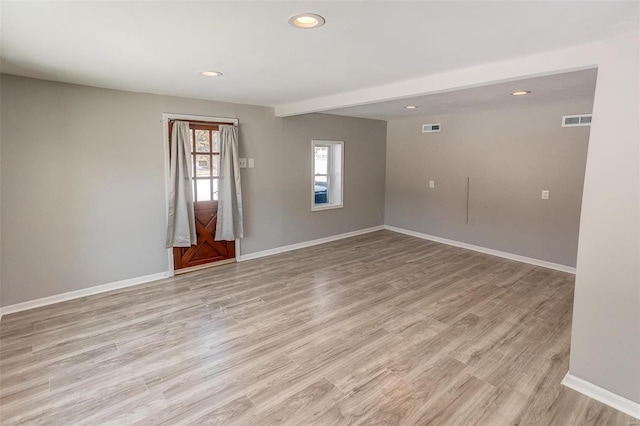 spare room featuring baseboards, visible vents, and light wood finished floors