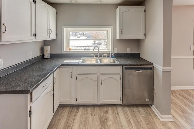 kitchen featuring dark countertops, white cabinets, a sink, and stainless steel dishwasher