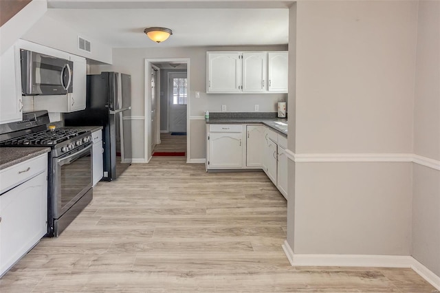 kitchen featuring dark countertops, visible vents, white cabinets, and stainless steel appliances